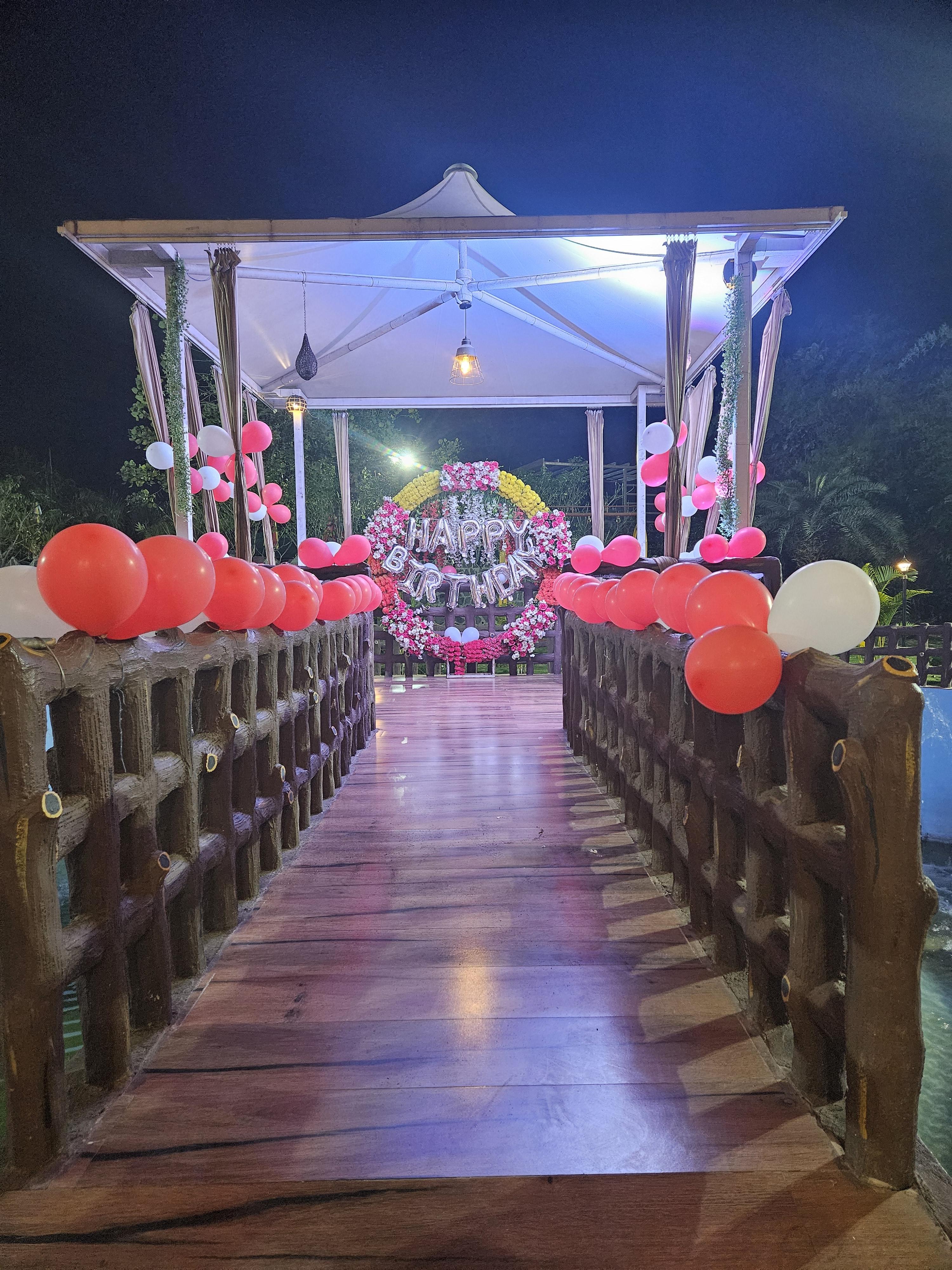 A serene and elegant outdoor setup, perfect for intimate gatherings and celebrations. The lush greenery, subtle floral arrangements, and neatly arranged seating create a welcoming and refreshing ambiance for guests to enjoy.