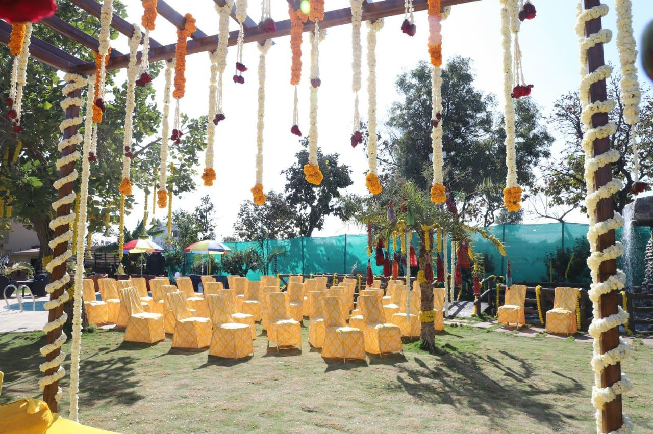 A serene and elegant outdoor setup, perfect for intimate gatherings and celebrations. The lush greenery, subtle floral arrangements, and neatly arranged seating create a welcoming and refreshing ambiance for guests to enjoy.