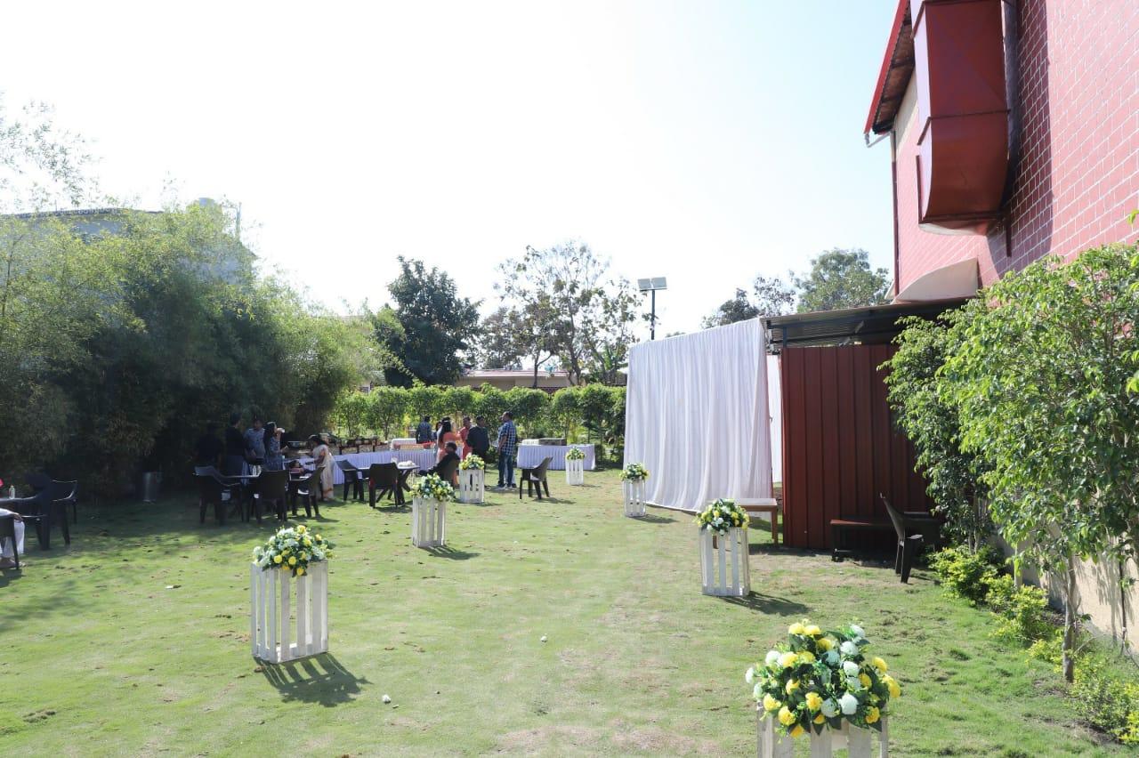 A serene and elegant outdoor setup, perfect for intimate gatherings and celebrations. The lush greenery, subtle floral arrangements, and neatly arranged seating create a welcoming and refreshing ambiance for guests to enjoy.